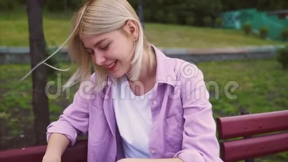在公园木制长凳上休息的迷人时髦女孩的肖像视频的预览图