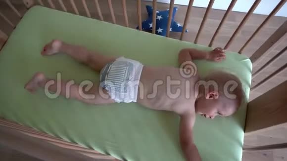 活跃的婴儿儿童尿布躺在木床上万向节运动视频的预览图
