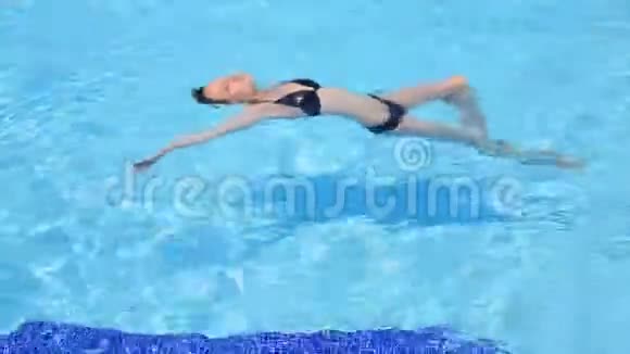 一个穿着黑色泳衣的漂亮女孩正在水里游泳和旋转视频的预览图