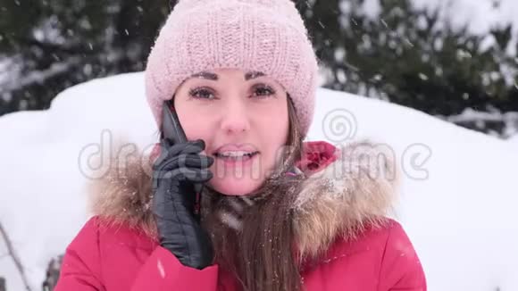 在冬天散步的时候一个开朗的年轻女人在打电话下雪视频的预览图
