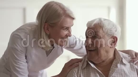 微笑着成熟善良的女人护士在和残疾老人说话视频的预览图