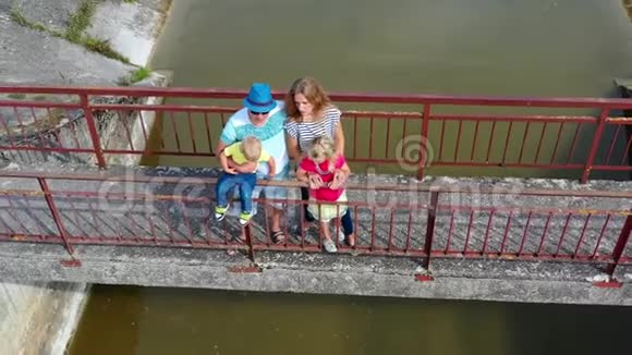 成年父母带着孩子欣赏废弃的坝景空中无人机移动视频的预览图