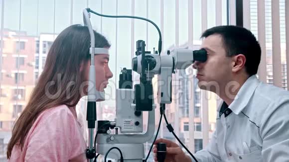 室内眼科治疗医生用专用机器检查年轻女子的视力宽敞视频的预览图