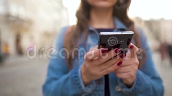 日落时分女人用智能手机走在老街上特写镜头慢动作通信社交网络视频的预览图