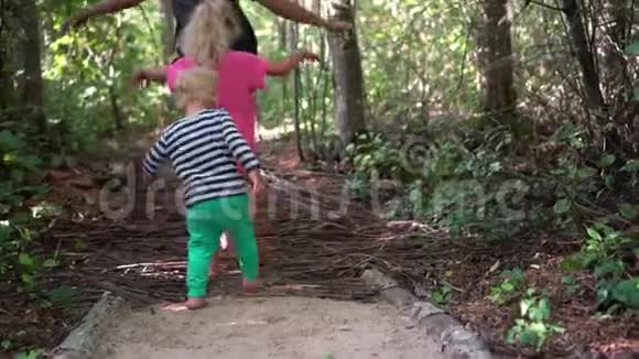 赤脚儿童男孩女孩和母亲的腿走在木棍小路上视频的预览图