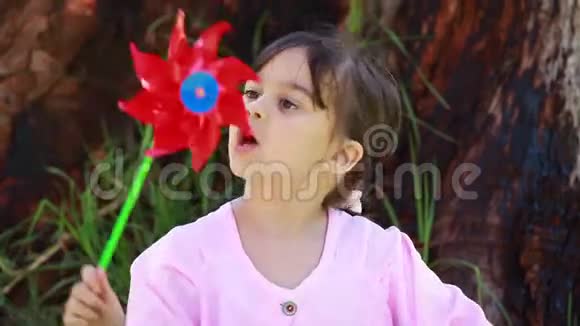 快乐的小女孩吹着风车视频的预览图