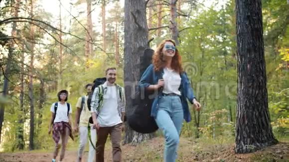 快乐的青年徒步旅行者背着背包在森林中漫步微笑着在夏天旅行视频的预览图