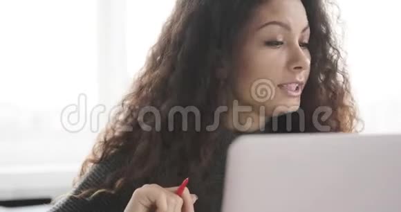 女商人在办公室里一边写笔记一边视频聊天视频的预览图