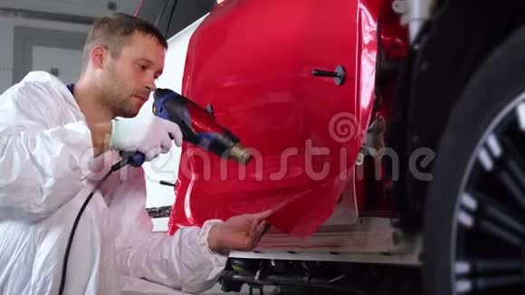 男人用风扇加热乙烯基胶带固定在车身上视频的预览图