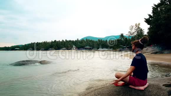 一个人坐在海边的石头上沉思带着恐惧症的莲花男视频的预览图