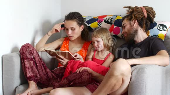 一家人在一起一个女人给丈夫和女儿读一本书视频的预览图