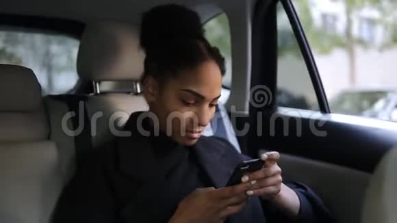 美丽的非洲裔美国妇女开车去参加一个重要的会议并在她的手机上打字乘客女孩视频的预览图