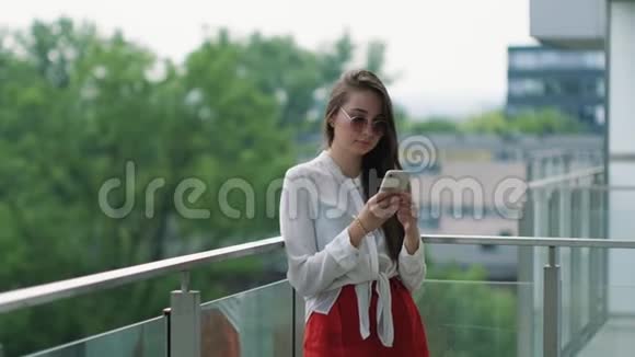 女人站在阳台上夏天用智能手机视频的预览图