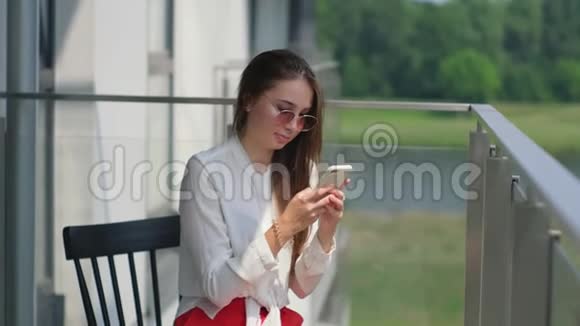 女士坐在阳台上在手机屏幕上打字视频的预览图
