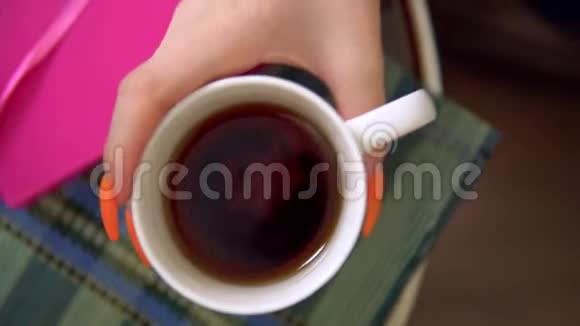 年轻女子在舒适的客厅软扶手椅上喝茶视频的预览图