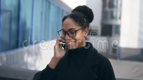 戴眼镜的开朗的女商人用智能手机说话充满感情的年轻非裔美国女商人用手机聊天视频的预览图
