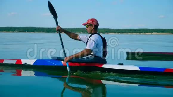 一名男子在独木舟上横渡水面的侧面景色视频的预览图