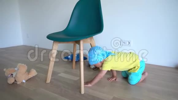 一个金发小男孩爬在椅子下面玩玩具熊视频的预览图