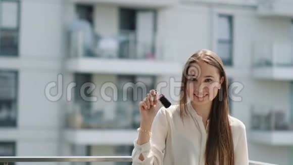 女人手里拿着车钥匙在阳台上微笑视频的预览图