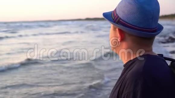 戴帽子的滑稽男子欣赏着令人惊叹的黄昏日落微笑着看着摄像机视频的预览图