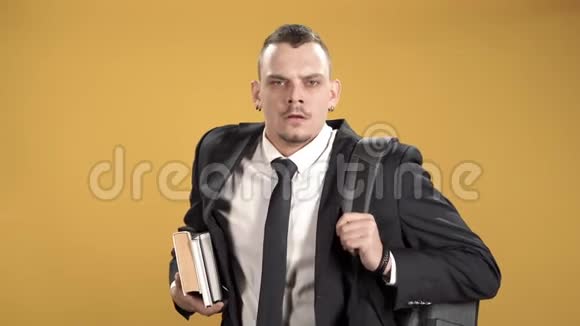 疲惫的男学生带着背包和黄色背景的书视频的预览图