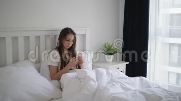 女人早上躺在床上用智能手机视频的预览图