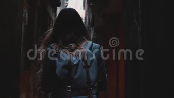 镜头跟随女游客背着背包沿着美丽的黑暗老城街道在威尼斯意大利慢动作视频的预览图