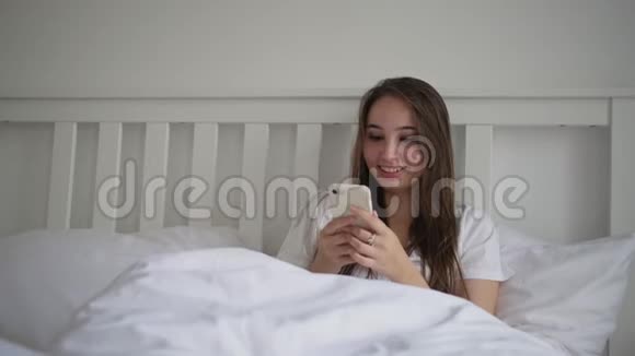 女士躺在床上看着智能手机的展示视频的预览图