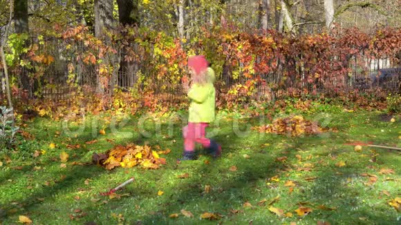 淘气的小女孩在花园里踢耙叶疯孩子在院子里嬉戏视频的预览图