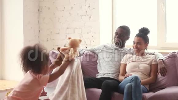 快乐的非洲父母喜欢在家看木偶戏视频的预览图