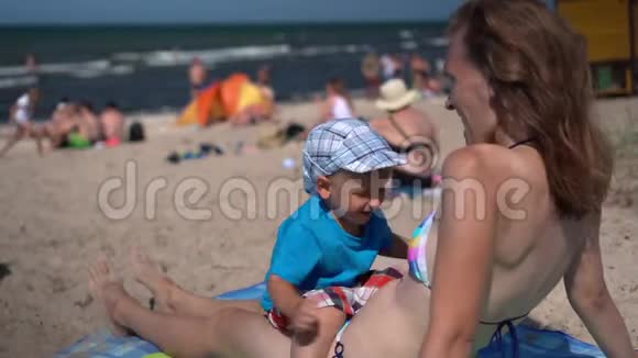 穿比基尼的性感妈妈肚子上有个小儿子躺在沙滩上视频的预览图
