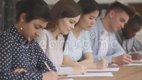 集中混合种族学生坐在教育讲座的桌子上视频的预览图