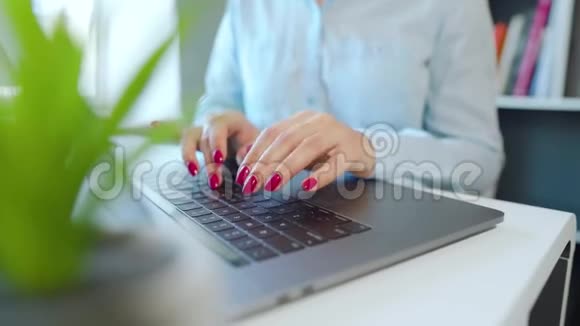 在笔记本电脑键盘上输入漂亮指甲的女性手视频的预览图