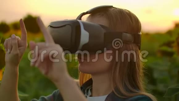 夏日傍晚日落时分女农场主在向日葵田上用VR眼镜视频的预览图