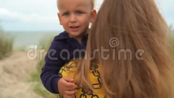 母亲抱着儿子走向海边视频的预览图