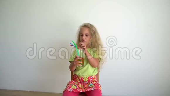 小金发女孩用四根吸管从玻璃杯里喝苹果汁万向节运动视频的预览图
