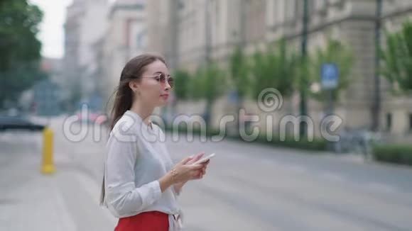 女子站在路边等待公共交通手里拿着手机视频的预览图