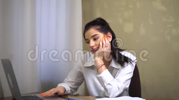 年轻的无聊困倦的员工看着笔记本电脑打哈欠懒惰的秘书办公室视频的预览图