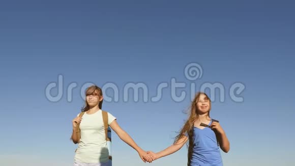 女孩们女游客牵着手走在蓝天的背景上特写镜头团队合作游客青少年妇女视频的预览图