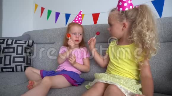 最好的朋友小女孩在木棒上玩糖果糖果坐着看电视视频的预览图