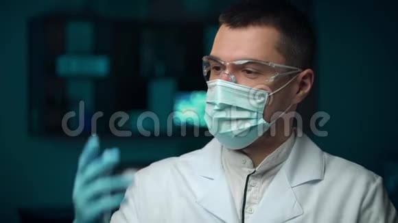 近距离观看严肃的年轻胡须男医生穿着白色职业外套在实验室戴上蓝色防护手套视频的预览图