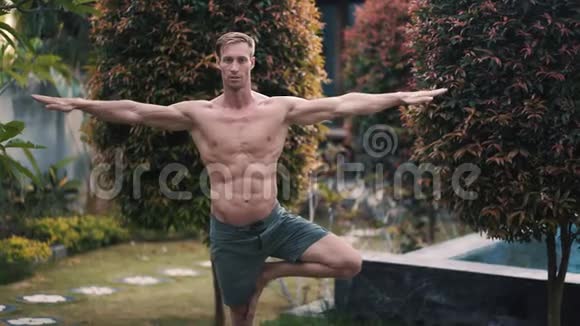 肌肉发达的男人做瑜伽运动背景绿色植物视频的预览图