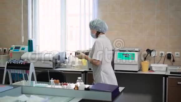 专业女性助理穿着白色实验室外套防护面罩帽子和乳胶手套带着测试架视频的预览图
