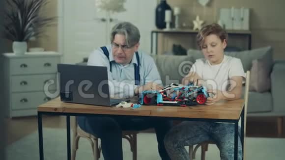 十几岁的男孩正和他的爷爷一起开玩具车视频的预览图