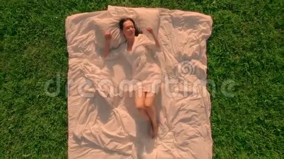 鸟瞰睡在草地上绿草如茵的女性视频的预览图