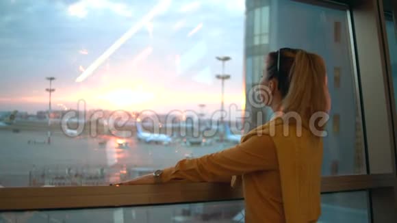 一位女士正在机场窗口附近听音乐视频的预览图