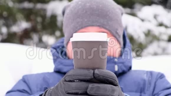 一个长胡子的人在冬天散步时喝咖啡下雪了视频的预览图