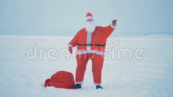 一个穿着圣诞服装的男人在一个带礼物的袋子附近跳舞关门了视频的预览图