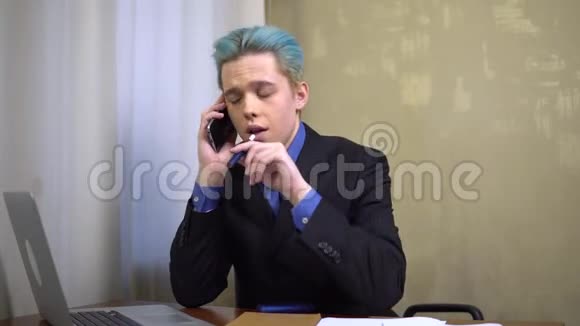 年轻商人在办公桌旁用电话吸烟在办公室工作视频的预览图