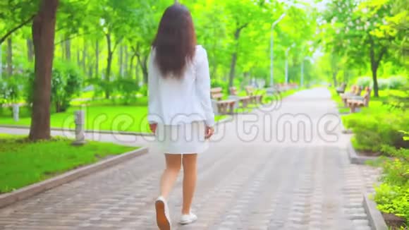 无法辨认的女人走在被绿树环绕的人行道上视频的预览图